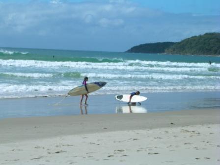 a couple of people carrying surfboards on a beach