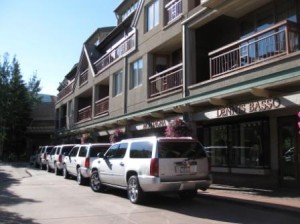 long shot of a row of cars parked in front of a building