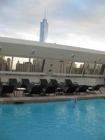 a pool with chairs and a city skyline in the background