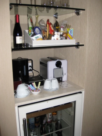 a small refrigerator with a coffee machine and a bottle of wine