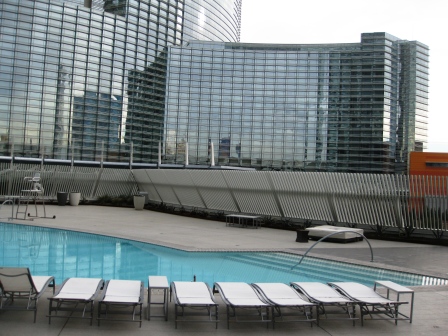 a pool with lounge chairs in front of a building