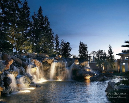 a waterfall with lights on rocks and trees