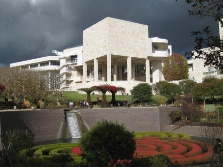 a large white building with columns and a fountain with Getty Center in the background