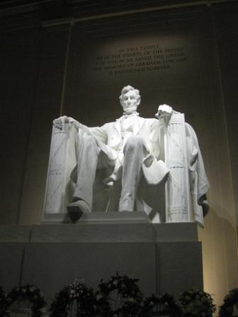 a statue of a man sitting on a pedestal with Lincoln Memorial in the background