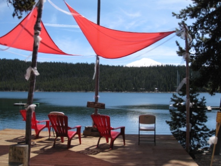 a deck with red chairs and a lake