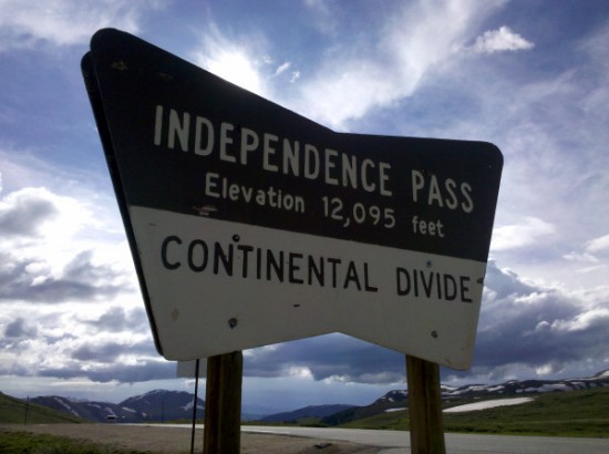 a sign with a road and mountains in the background