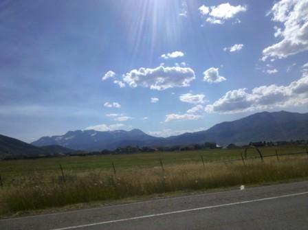 a road with a field and mountains in the background