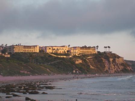 long shot of a beach with a building on the hill