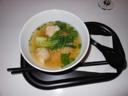 a bowl of soup with vegetables and chopsticks
