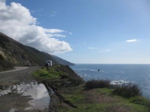 a road with a body of water and a truck