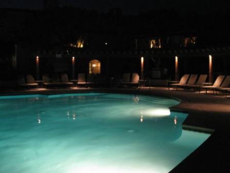 a pool at night with a deck and chairs