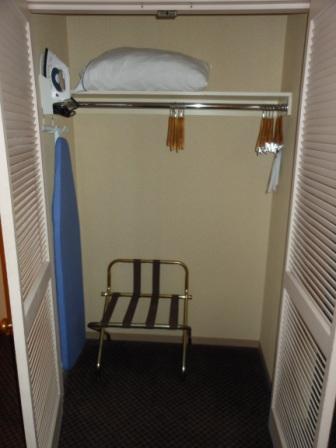 a small closet with a bed and a towel rack