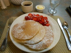 a plate of pancakes with strawberries and butter