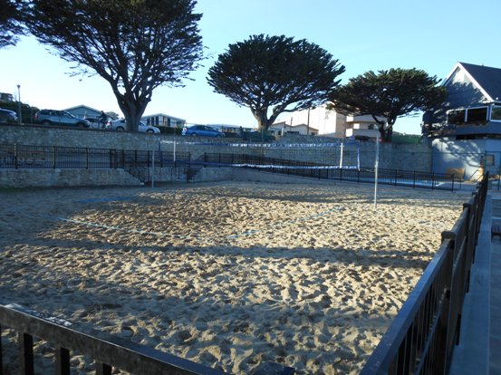 a sand volleyball court with trees in the background