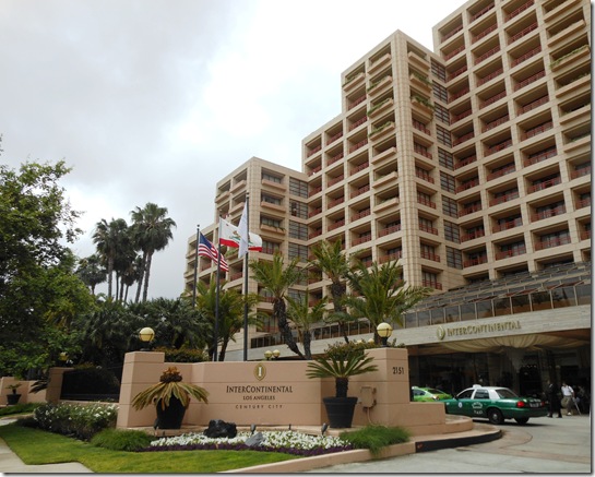 a large building with palm trees and flags