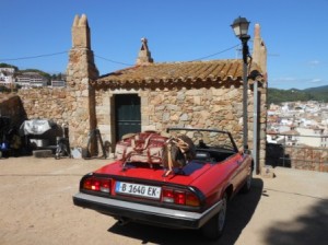 a red convertible car with luggage on the roof