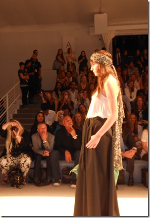 a woman on a runway with a crowd watching