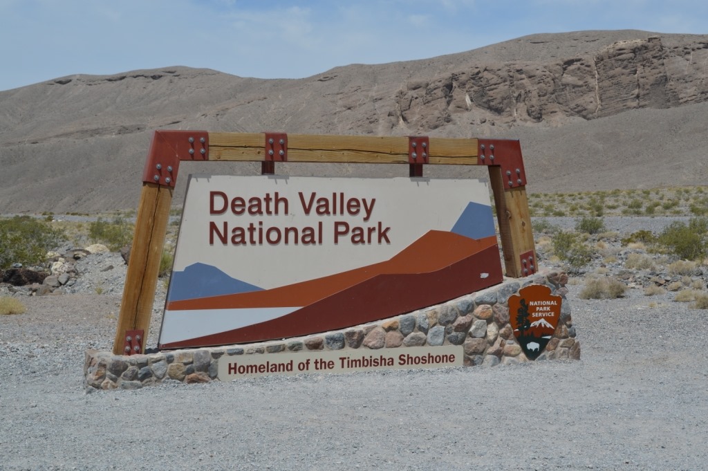 a sign in the desert with Death Valley National Park in the background
