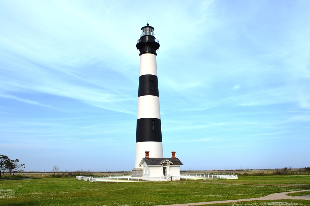 a black and white lighthouse on a grassy field