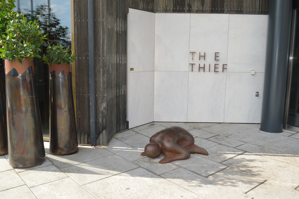 a statue of a person lying on the ground outside of a building