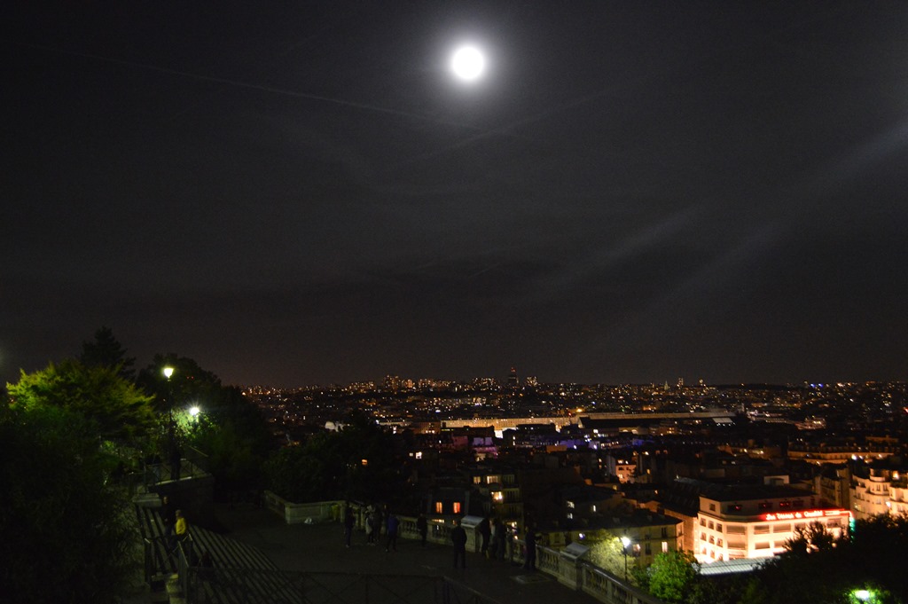 a city at night with the moon in the sky