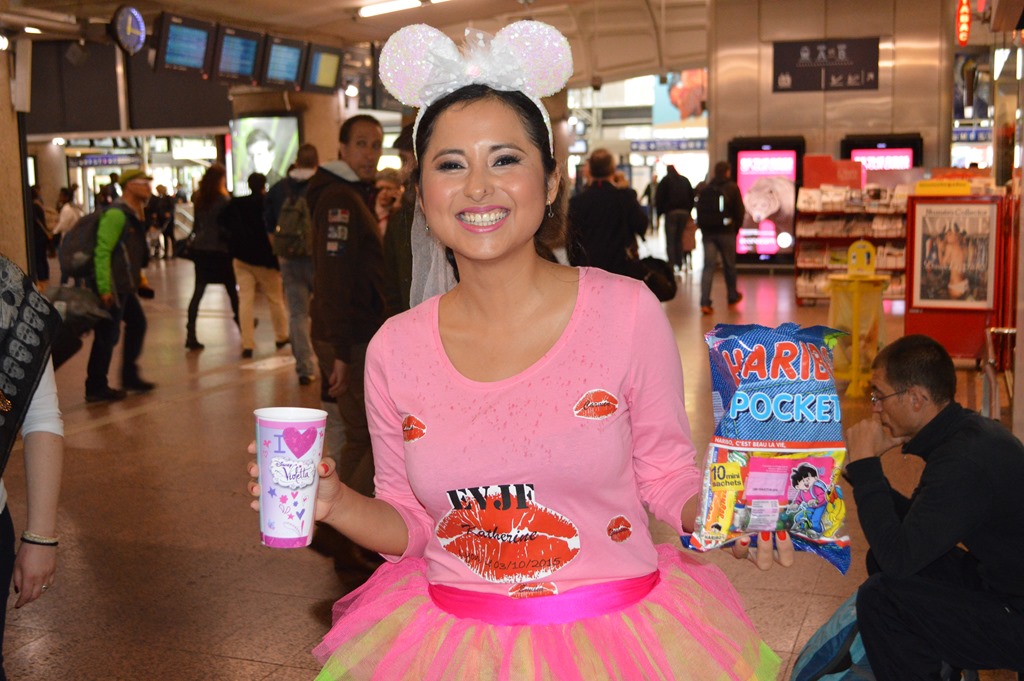 a woman in a tutu holding a bag of snacks and a cup