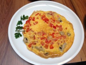 a plate of omelette with tomatoes and mushrooms