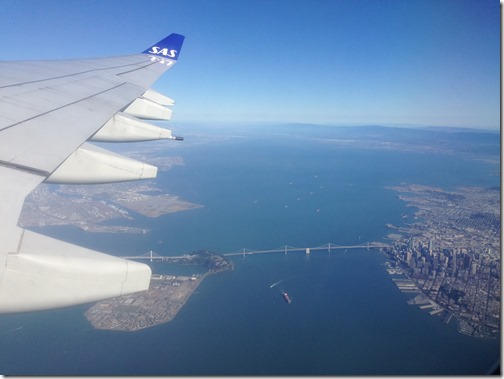 an airplane wing with a bridge and a city