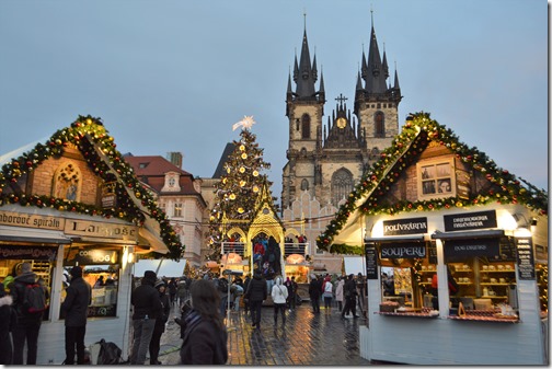 a group of people walking in front of a building with a christmas tree