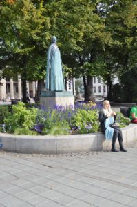 a woman sitting on a stone bench in front of a statue