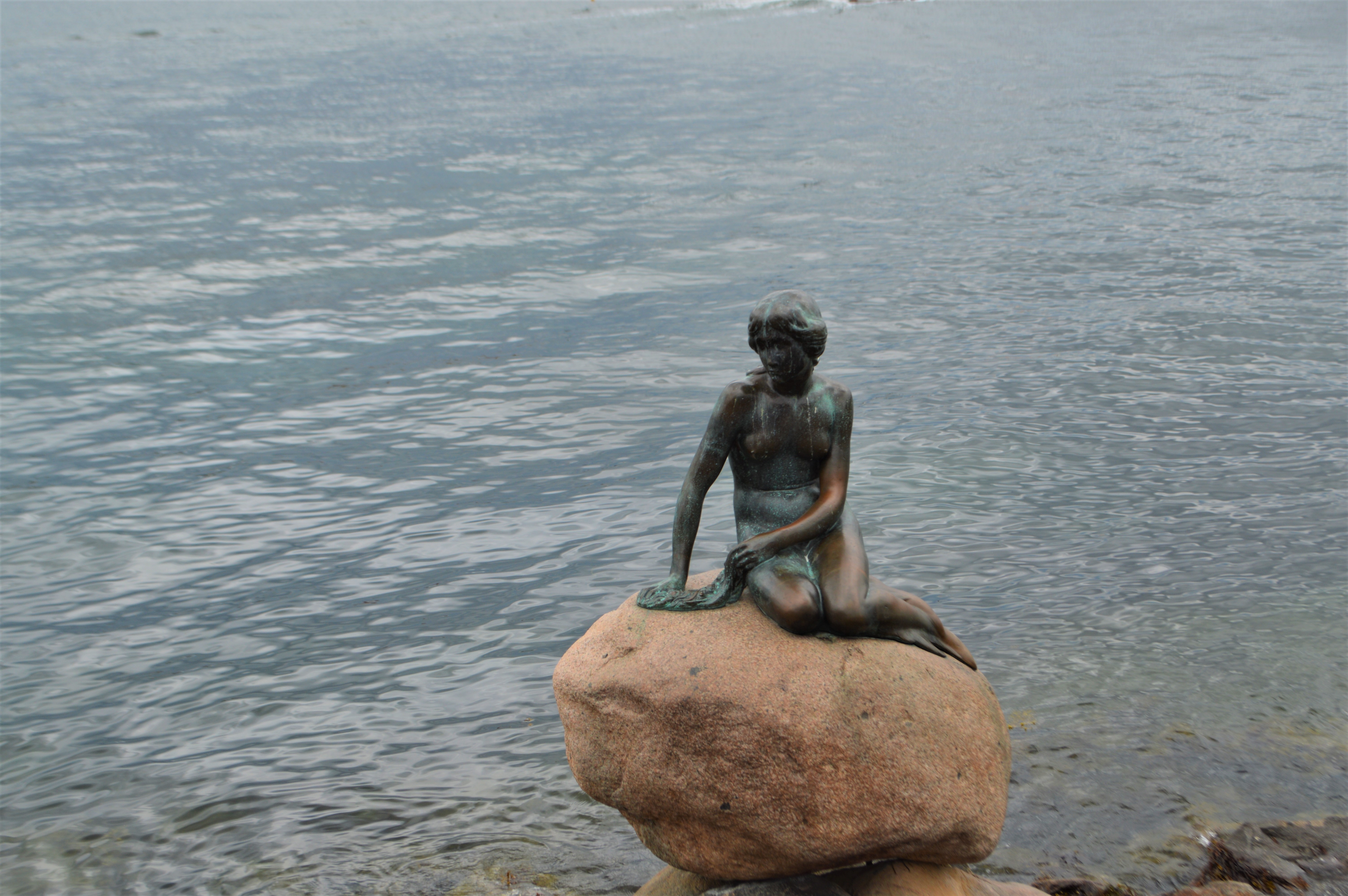 a statue of a mermaid sitting on a rock