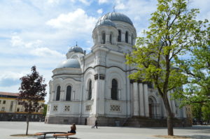 a white building with domes and a couple people sitting on a bench