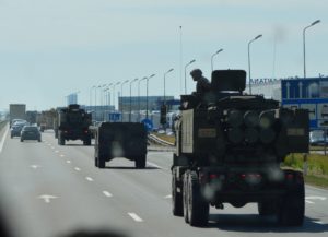 a group of military vehicles driving on a highway