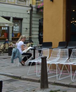 a woman sitting at a table outside a cafe