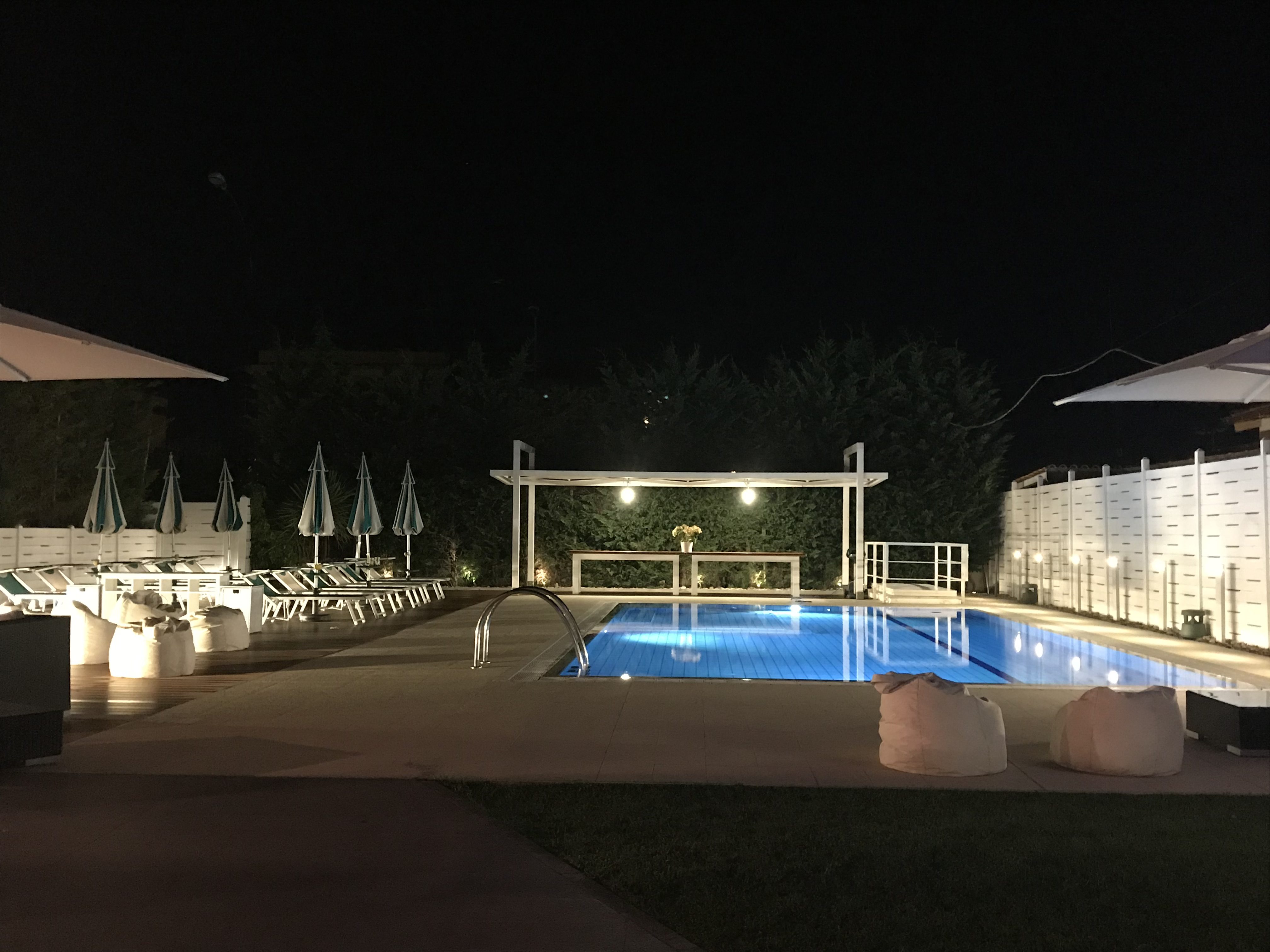 a pool with umbrellas and chairs at night