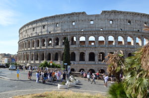 a large circular building with many arches with Colosseum in the background