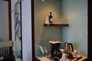 a coffee maker and wine glasses on a shelf