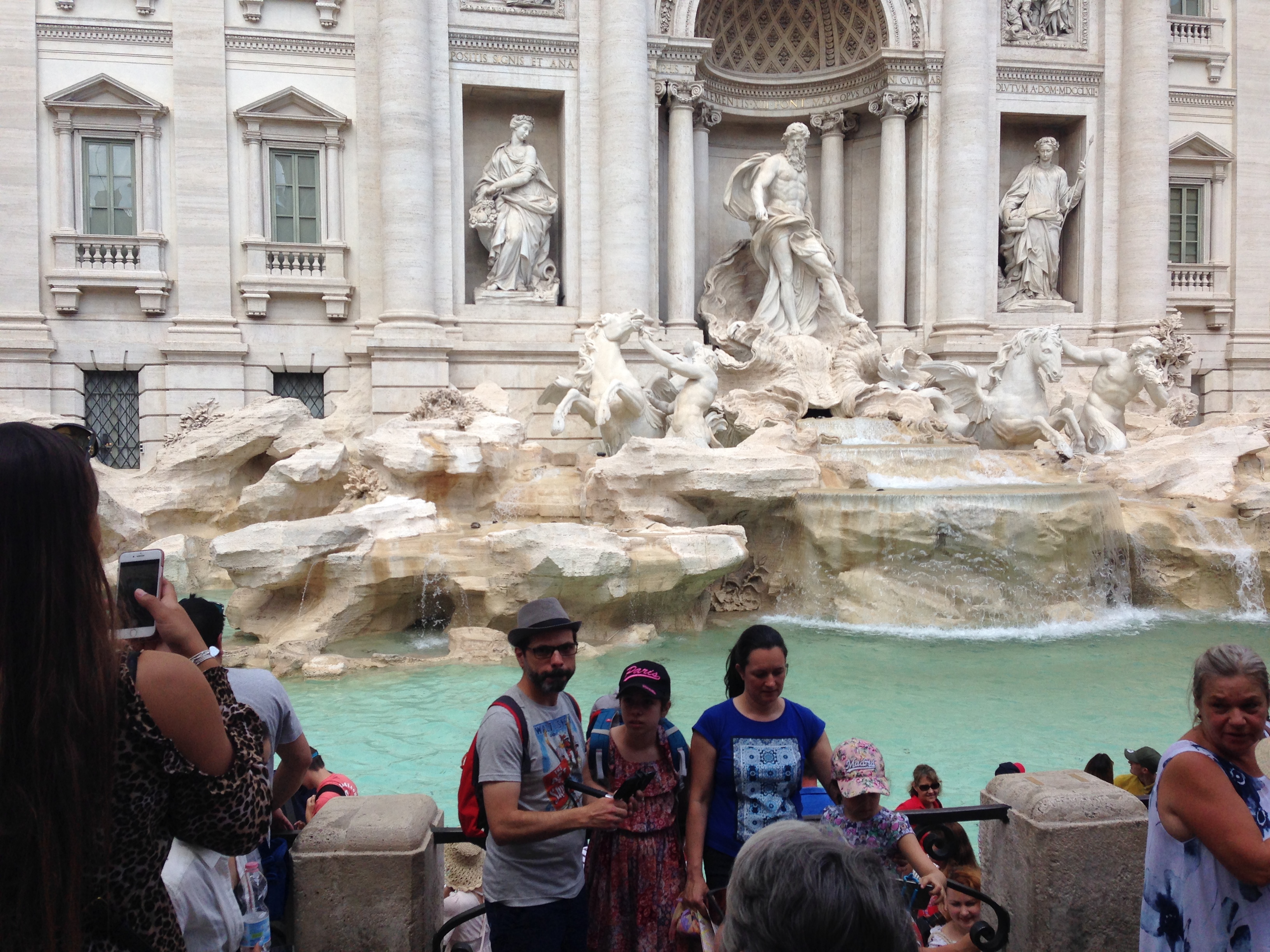 a group of people standing in front of a fountain with Trevi Fountain in the background