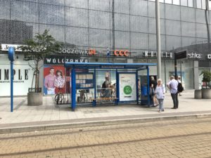 a bus stop with people standing in front of a building