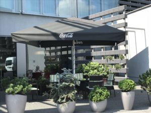 a patio with a black umbrella and plants