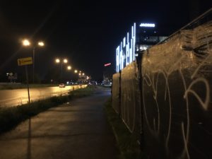a sidewalk with a wall and lights at night