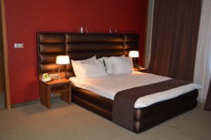 a bed with a brown headboard and a red wall