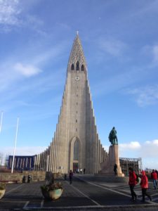 a tall building with a pointed roof with Hallgrímskirkja in the background