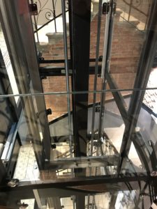 a glass elevator with a brick wall