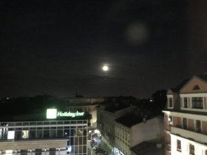 a city at night with the moon in the sky