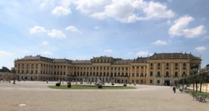 a large building with a circular courtyard with Schönbrunn Palace in the background