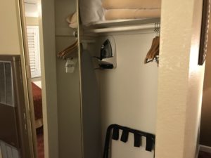 a closet with a iron and clothes on the wall