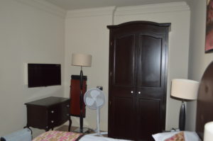 a room with a tall dark closet and a fan