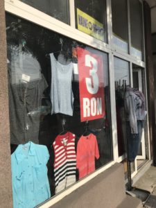 a storefront with a sign and clothes in it