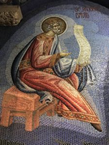 a mosaic of a man sitting on a stool